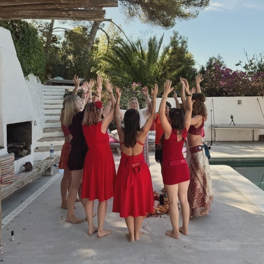 Círculo de mujeres con los brazos alzados en un ritual al aire libre